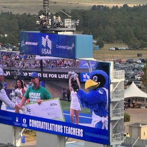 Encompass Heights Elementary School teacher Mat Pace accepts a check from the US Air Force Academy